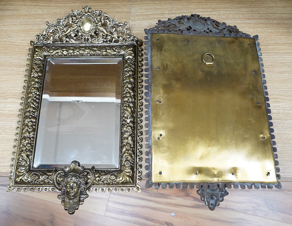 A pair of French brass repoussé mirrors with an ornate putti top and mask decorated bottom, 49cm high. Condition - good